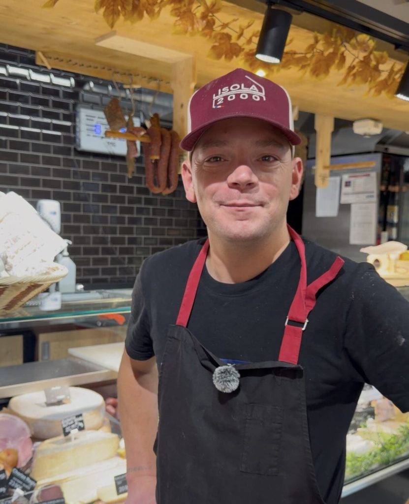 Équipier du supermarché Utile Isola 2000 au rayon boucherie et fromage à la coupe
